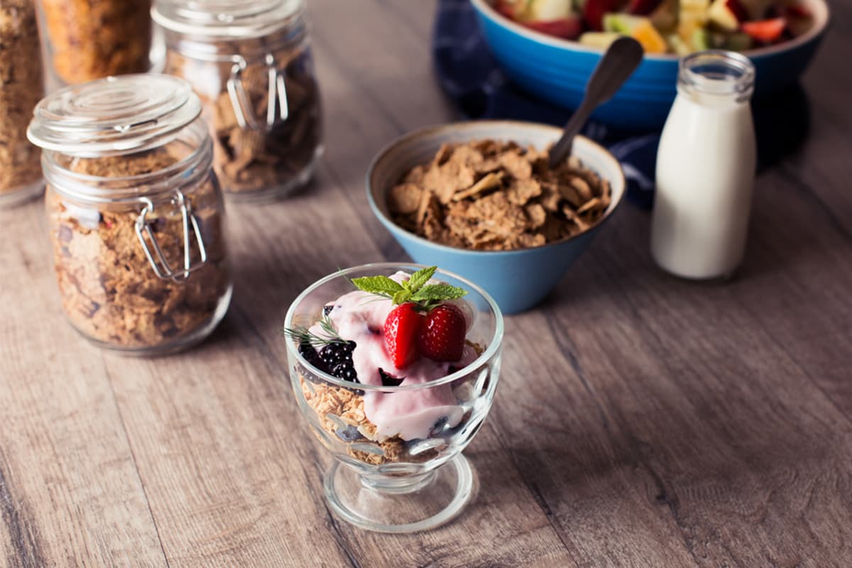 Granola, cereal, milk and a yoghurt pot with berries