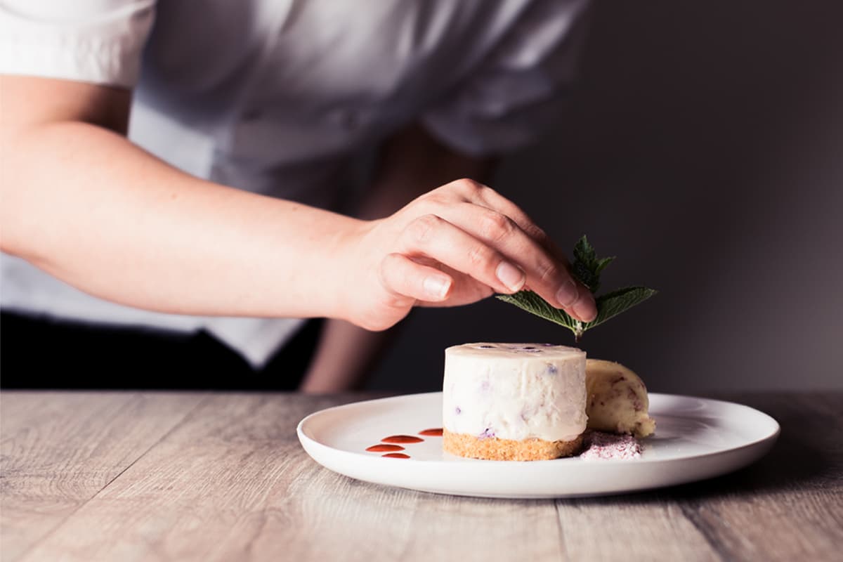 Chef garnishing a plated cheesecake