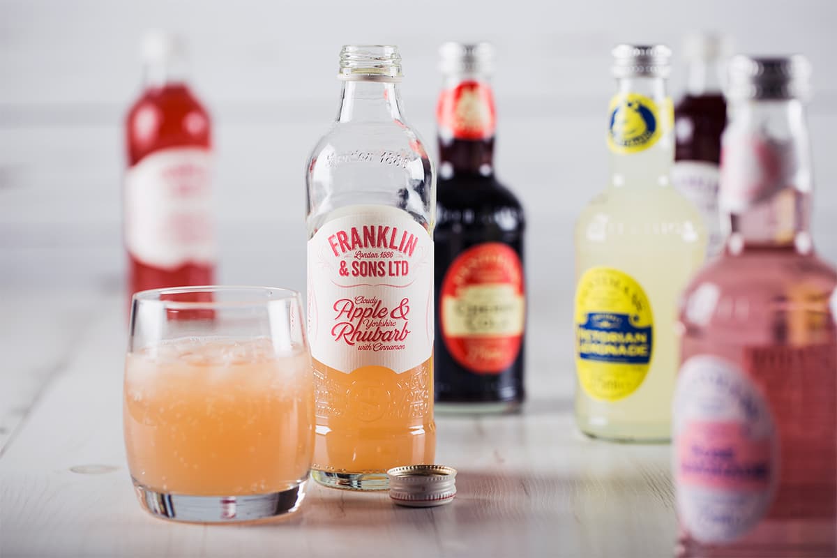 Bottled soft drinks with a glass of sparkling rhubarb lemonade