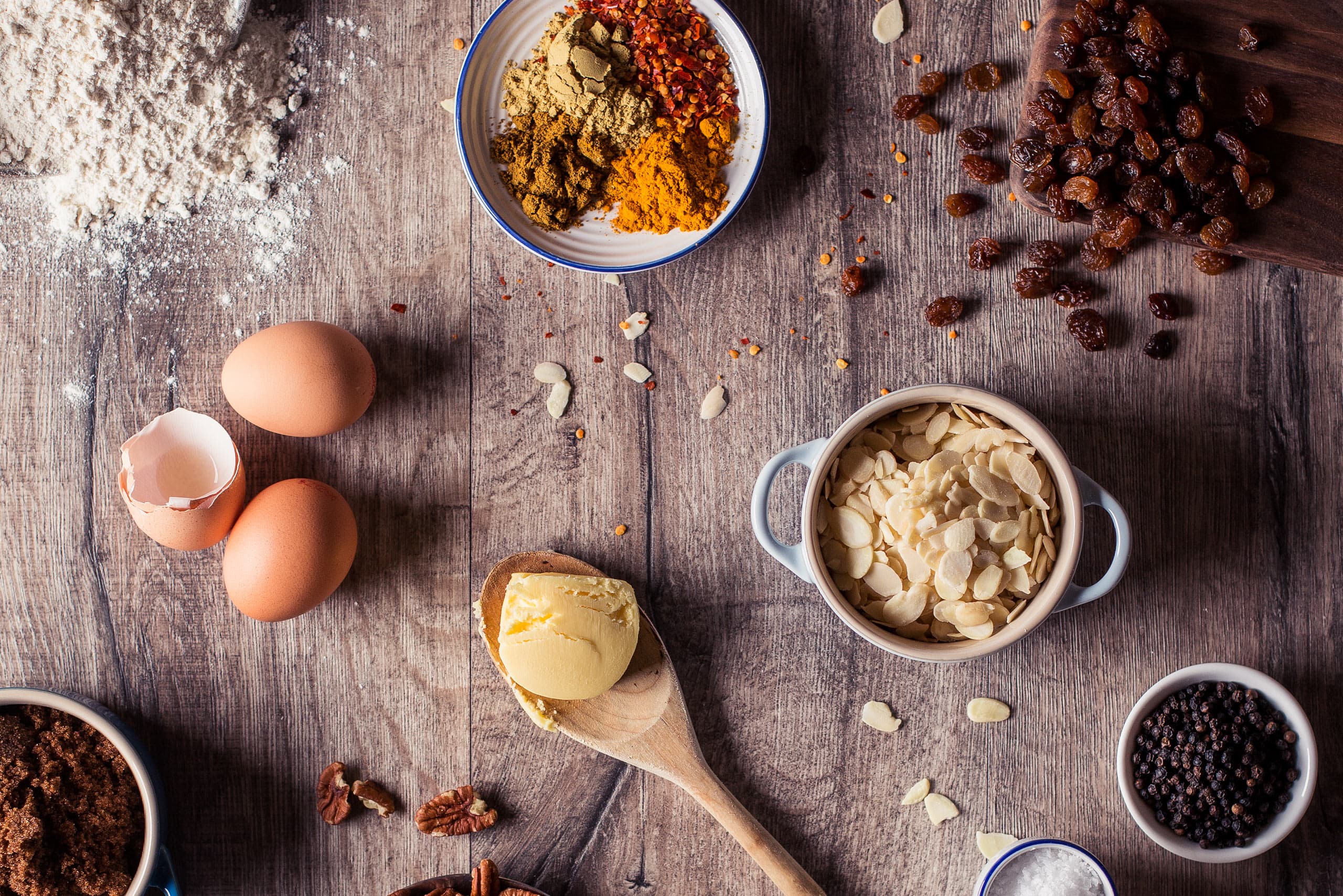 Baking ingredients: eggs, flour, almonds, spices and raisins on a wooden table